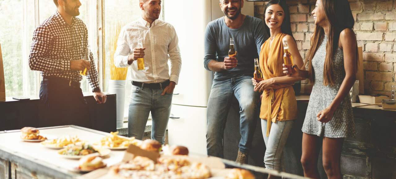 Group of people enjoying food and drinks in kitchen